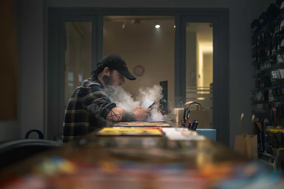 Vape shop employee behind the counter with product shelves in background